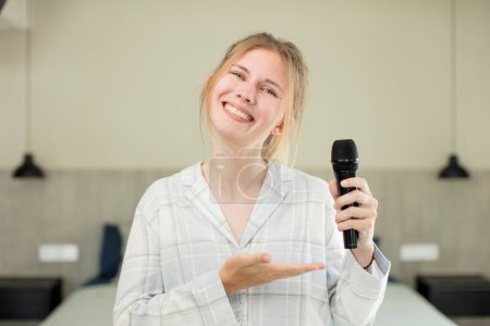 Photo for Young pretty woman smiling cheerfully, feeling happy and showing a concept. microphone concept - Royalty Free Image