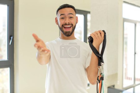 Téléchargez les photos : Homme beau arabe homme arabe souriant heureux et offrant ou montrant un concept. concept de fitness - en image libre de droit