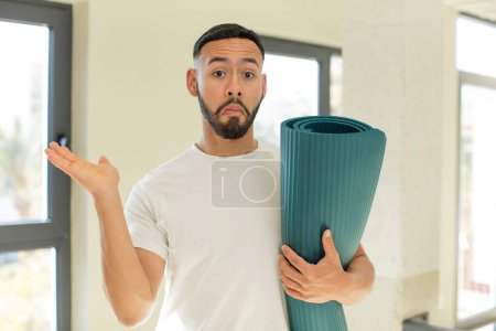 Photo for Arab handsome man arab man shrugging, feeling confused and uncertain. yoga matt concept - Royalty Free Image
