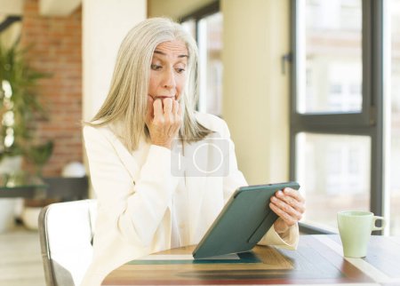 Foto de Anciana bonita mujer sintiendo miedo, preocupado o enojado y mirando a un lado con una pantalla táctil - Imagen libre de derechos