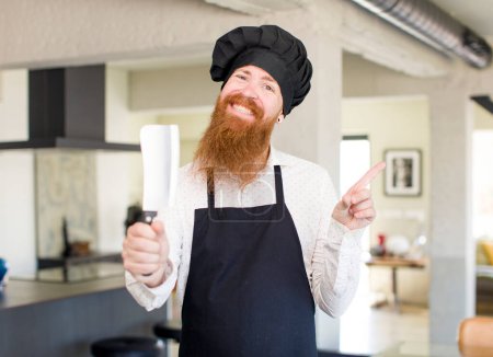 Photo for Red hair man smiling cheerfully, feeling happy and pointing to the side. chef concept - Royalty Free Image