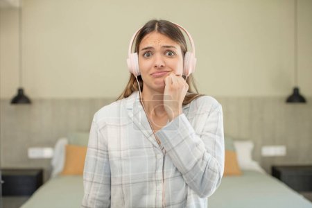 Photo for Young pretty woman feeling scared, worried or angry and looking to the side. headphones concept - Royalty Free Image