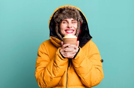 Foto de Young adult pretty woman wearing anorak and winter hat and holding a take away coffee - Imagen libre de derechos