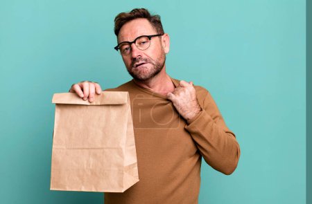 Photo for Middle age man feeling stressed, anxious, tired and frustrated. take away paper bag - Royalty Free Image