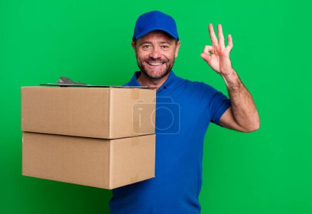 Foto de Hombre de mediana edad sintiéndose feliz, mostrando aprobación con gesto bien. Repartidor de panaderos. envasador entrega hombre - Imagen libre de derechos