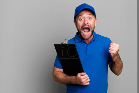 Photo for Middle age man feeling shocked,laughing and celebrating success. company employee with an inventory - Royalty Free Image