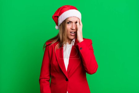 Photo for Pretty blonde woman feeling bored, frustrated and sleepy after a tiresome. christmas and santa hat concept - Royalty Free Image