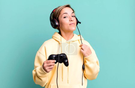 Foto de Mujer rubia bonita buscando arrogante, exitoso, positivo y orgulloso. gamer con auriculares y un controlador - Imagen libre de derechos
