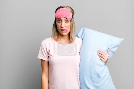 Foto de Mujer rubia bonita buscando desconcertado y confundido. concepto de pijamas y ropa de dormir - Imagen libre de derechos
