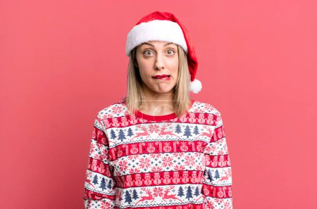 Foto de Pretty blonde woman looking puzzled and confused. christmas and santa hat concept - Imagen libre de derechos