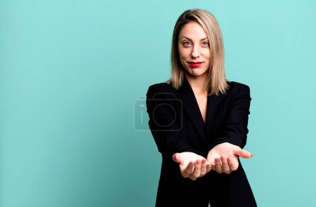 Photo for Pretty blonde woman smiling happily with friendly and  offering and showing a concept. businesswoman concept - Royalty Free Image
