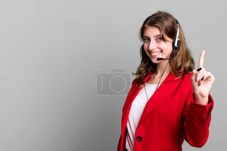 Téléchargez les photos : Caucasienne jolie femme souriant fièrement et en toute confiance faisant numéro un. concept d'agent de télémarketing - en image libre de droit