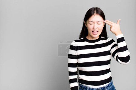 Foto de Bastante asiático mujer buscando infeliz y estresado, suicidio gesto haciendo arma signo - Imagen libre de derechos