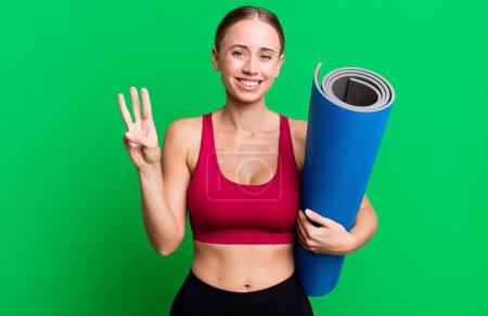 Téléchargez les photos : Caucasienne jolie femme souriante et amicale, montrant numéro trois. concept de fitness et yoga - en image libre de droit