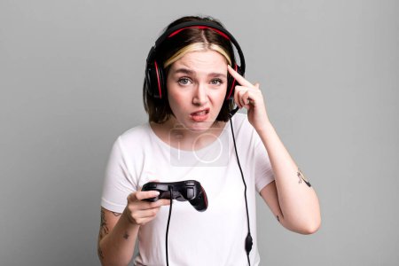 Photo for Young pretty woman feeling confused and puzzled, showing you are insane. gamer concept - Royalty Free Image