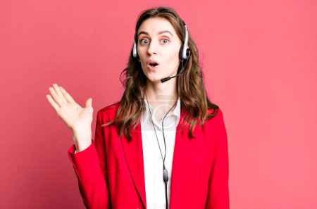 Photo for Young pretty woman looking surprised and shocked, with jaw dropped holding an object. telemarketer concept - Royalty Free Image