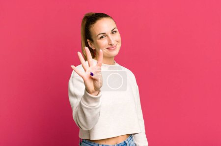 Photo for Young pretty woman smiling and looking friendly, showing number four - Royalty Free Image