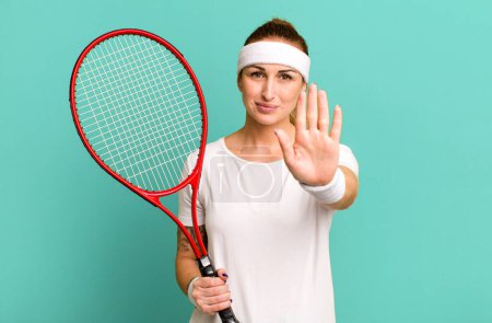 Téléchargez les photos : Jeune jolie femme regardant sérieusement montrant la paume ouverte faisant geste d'arrêt. concept de tennis - en image libre de droit
