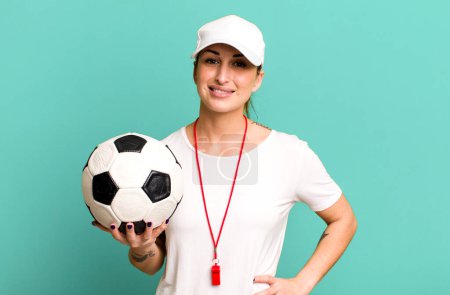Photo for Young pretty woman smiling happily with a hand on hip and confident. soccer coach concept - Royalty Free Image