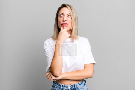 Photo for Blonde adult woman thinking, feeling doubtful and confused, with different options, wondering which decision to make - Royalty Free Image