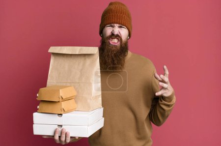 Téléchargez les photos : Jeune adulte cheveux roux barbu homme cool avec un sac en papier avec emporter de la nourriture - en image libre de droit