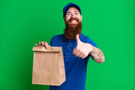 Foto de Joven adulto pelo rojo barbudo fresco entrega hombre con una bolsa de papel - Imagen libre de derechos