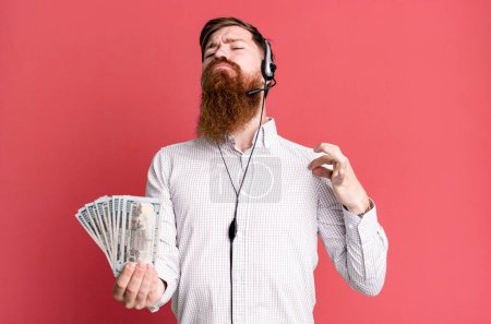 Photo for Young adult red hair bearded cool agent man with headset and dollar banknotes - Royalty Free Image