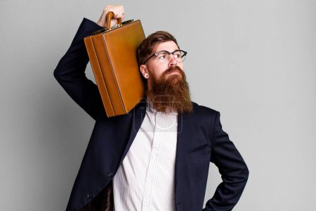 Téléchargez les photos : Jeune adulte cheveux roux barbu homme d'affaires cool avec une valise en cuir - en image libre de droit