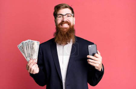 Photo for Young adult red hair bearded cool businessman with bills and a phone - Royalty Free Image