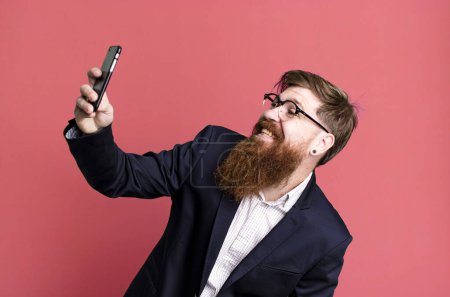 Photo for Young adult red hair bearded cool businessman using his smartphone - Royalty Free Image