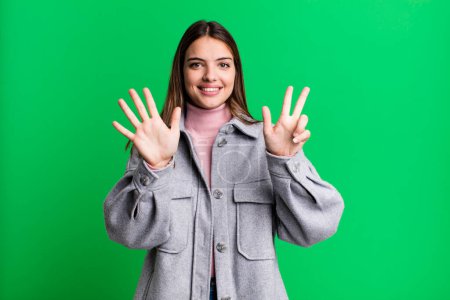 Foto de Pretty young adult woman smiling and looking friendly, showing number eight or eighth with hand forward, counting down - Imagen libre de derechos