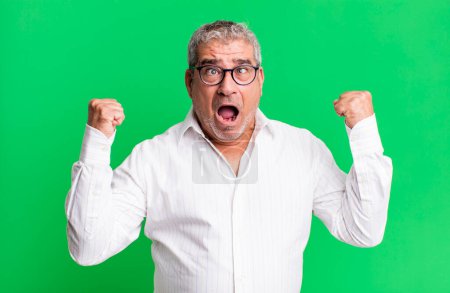 Photo for Middle age senior man shouting aggressively with an angry expression or with fists clenched celebrating success - Royalty Free Image