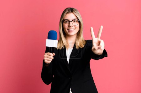 Photo for Young pretty woman smiling and looking friendly, showing number two. presenter or journalist concept - Royalty Free Image