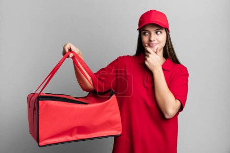 Foto de Young pretty woman smiling with a happy, confident expression with hand on chin. pizza delivery concept - Imagen libre de derechos