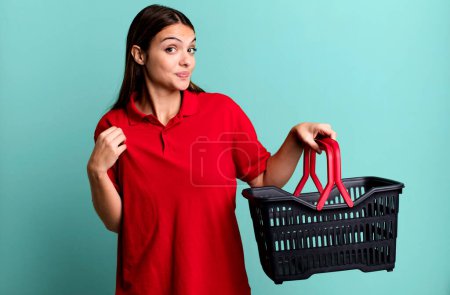 Téléchargez les photos : Young pretty woman looking arrogant, successful, positive and proud. empty shopping basket concept - en image libre de droit