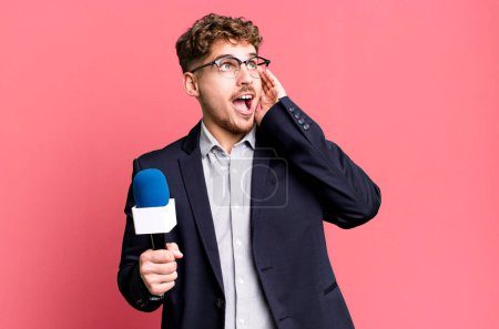 Téléchargez les photos : Jeune homme caucasien adulte se sentant heureux, excité et surpris. journaliste ou présentateur avec un microphone - en image libre de droit