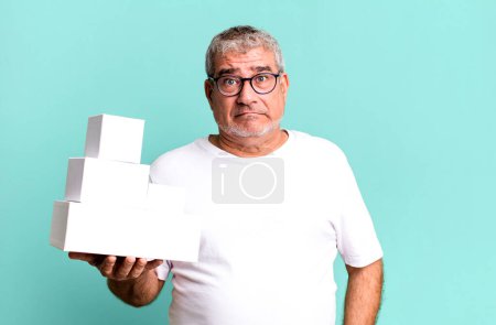 Photo for Middle age senior man looking puzzled and confused. different packages blank boxes - Royalty Free Image