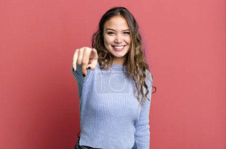 Photo for Young pretty woman pointing at camera with a satisfied, confident, friendly smile, choosing you - Royalty Free Image