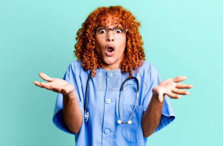 Téléchargez les photos : Cheveux roux jolie femme se sentant extrêmement choqué et surpris. concept d'infirmière - en image libre de droit