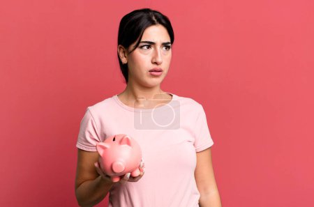 Photo for Feeling sad, upset or angry and looking to the side. with a piggy bank - Royalty Free Image