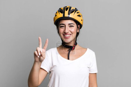 Foto de Sonriendo y luciendo amigable, mostrando el número dos. concepto de casco de bicicleta - Imagen libre de derechos