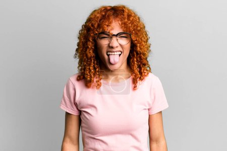 Photo for Redhair pretty woman feeling disgusted and irritated, sticking tongue out, disliking something nasty and yucky - Royalty Free Image