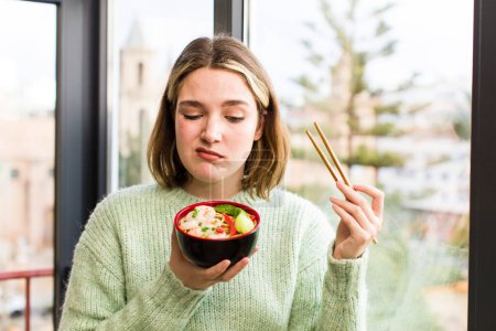 Foto de Mujer joven y bonita comiendo un plato de fideos chinos ramen. casa de diseño de interiores - Imagen libre de derechos