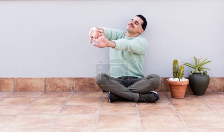 Téléchargez les photos : Jeune bel homme gardant et assis sur le sol à l'extérieur - en image libre de droit