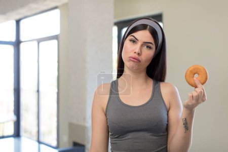 Photo for Pretty young woman feeling sad and whiney with an unhappy look and crying. donut concept - Royalty Free Image