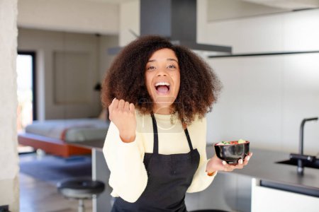 Téléchargez les photos : Jolie afro femme noire se sentant choquée, riant et célébrant le succès. nouilles japonaises concept ramen - en image libre de droit