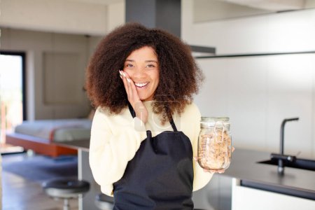 Téléchargez les photos : Jolie afro femme noire se sentant heureuse et étonnée de quelque chose d'incroyable. concept de cookies maison - en image libre de droit