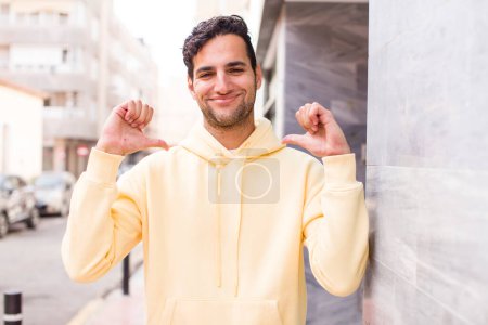 Téléchargez les photos : Jeune homme hispanique se sentant fier, arrogant et confiant, regardant satisfait et réussi, pointant vers soi-même - en image libre de droit