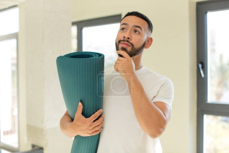Téléchargez les photos : Bel homme arabe homme arabe souriant avec une expression heureuse et confiante avec la main sur le menton. yoga concept mat - en image libre de droit