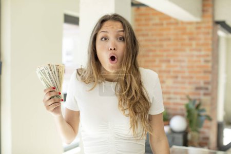 Foto de Pretty woman feeling extremely shocked and surprised. dollar banknotes concept - Imagen libre de derechos